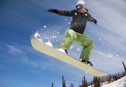 Snowboarder jumping through air with deep blue sky in background
